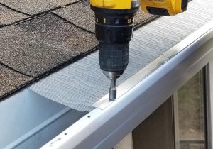 A roofer drilling into a gutter